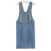 A denim cross-back apron with a V-neck and front pockets is displayed on a hanger.