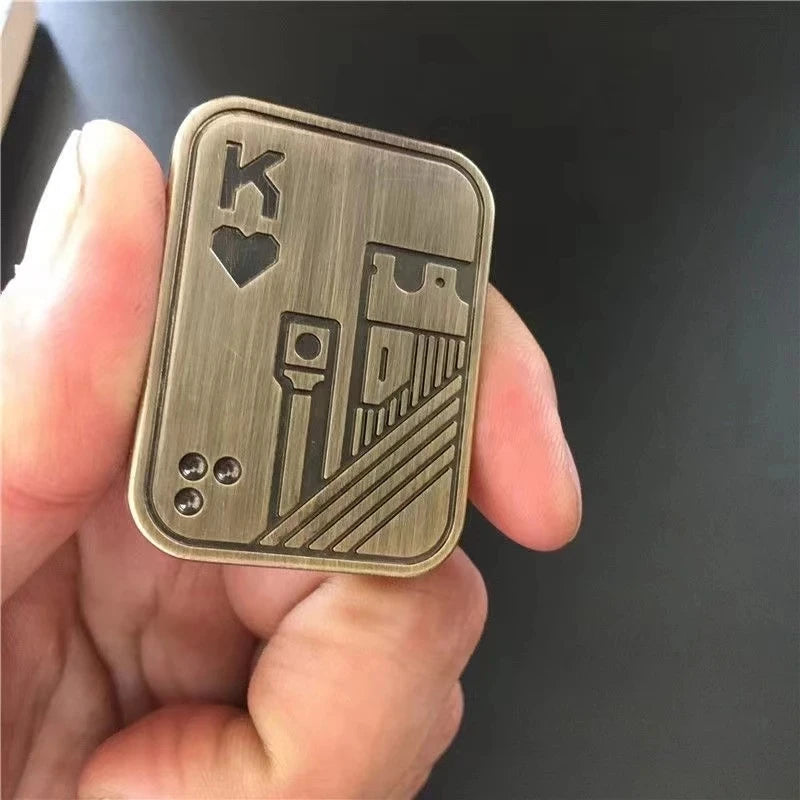 A hand holds a metal fidget slider toy engraved with a King of Hearts design.