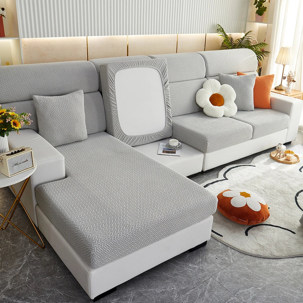 A modern gray sofa slipcover with white accents and decorative pillows is shown in a bright living room setting.