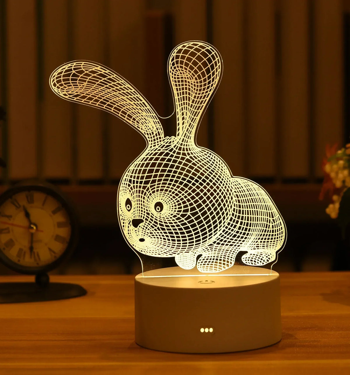 A white wireframe rabbit 3D illusion LED night light lamp resting on a wooden surface.