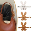 A brown leather handbag features several cute bunny-shaped charms attached to the strap.