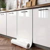 White cabinet doors with silver handles and a roll of pearlescent pink marble peel and stick wallpaper