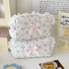A white cosmetic pouch with a vintage rose print and pink satin ribbon bow, featuring delicate lace trim.