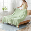 A light green ice silk blanket is draped over a wooden bed, with frost effects visible on the fabric and surrounding area.
