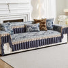 A navy blue sofa covered with an ornate patterned fabric and decorative trim, featuring accent pillows.