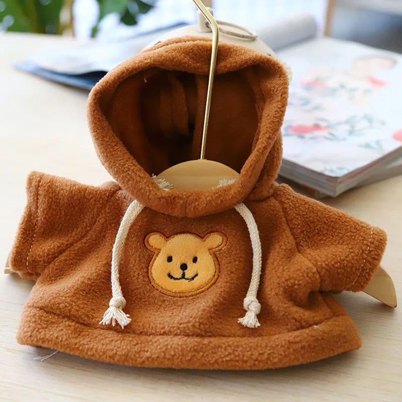 A brown knitted hoodie with a yellow bear face design, displayed on a light wooden surface.