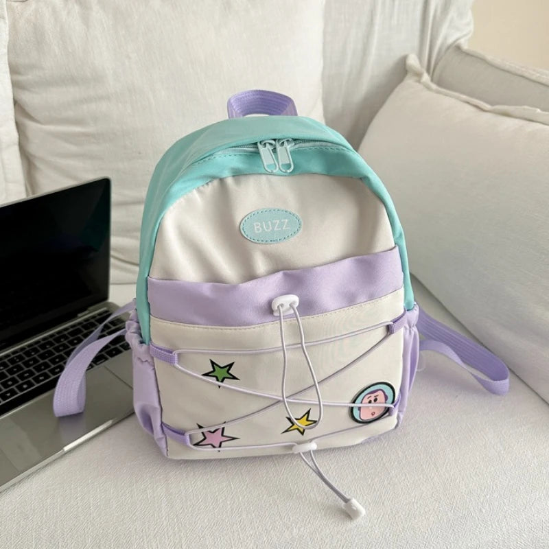 A pastel blue and lavender backpack with a white cow print design resting on a white surface.