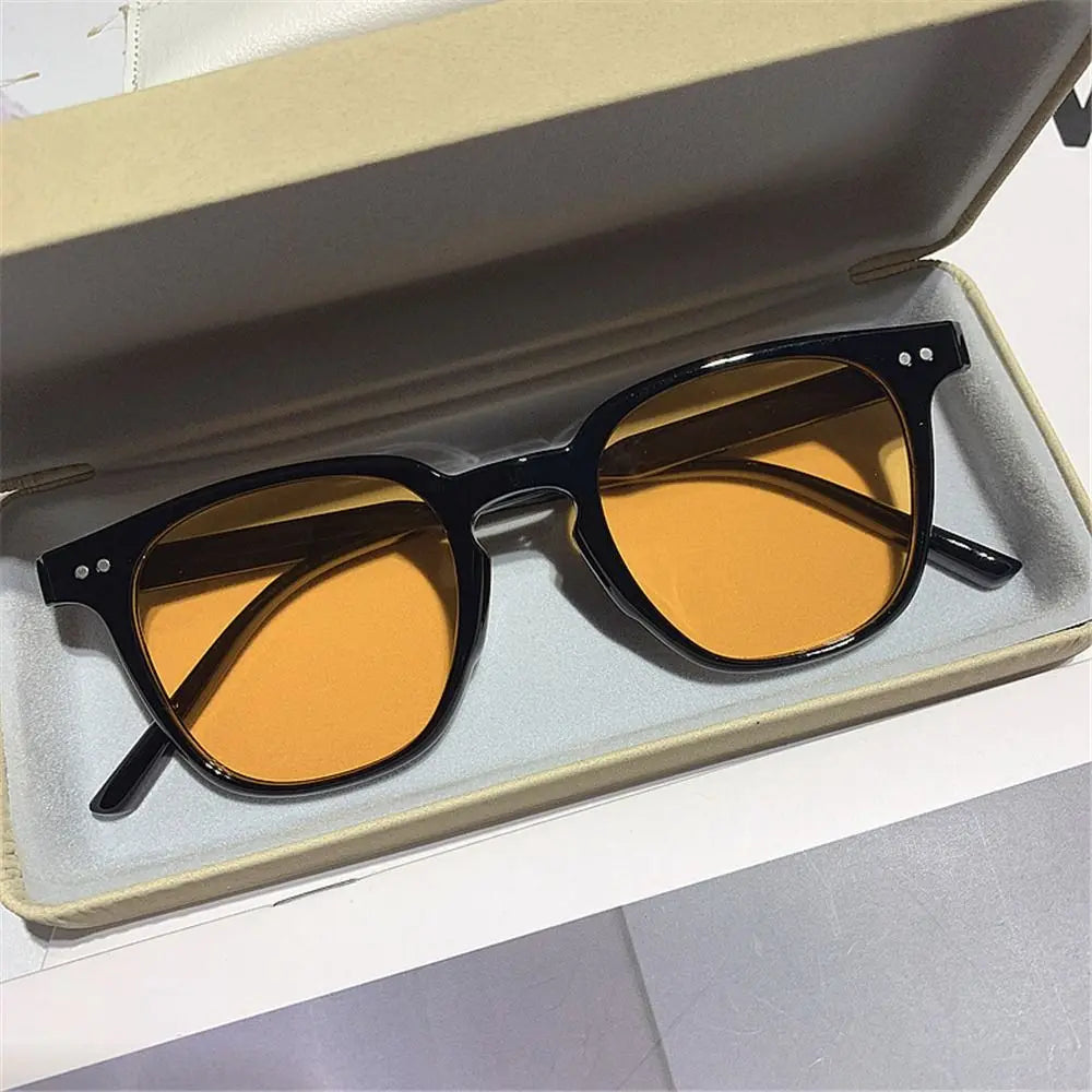 Vintage square sunglasses with dark frames and amber tinted lenses displayed in a light-colored box.