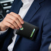 A hand is holding a black slim leather bifold wallet with an RFID blocking feature against a navy blue suit jacket.