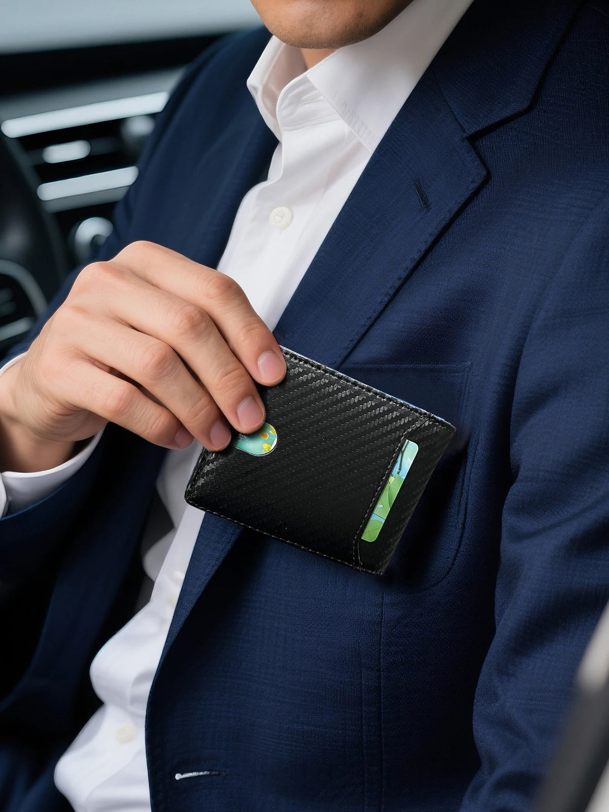 A hand is holding a black slim leather bifold wallet with an RFID blocking feature against a navy blue suit jacket.