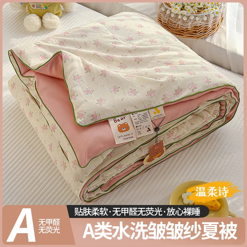 A lightweight summer quilt with a playful cartoon print featuring pink and cream colors.