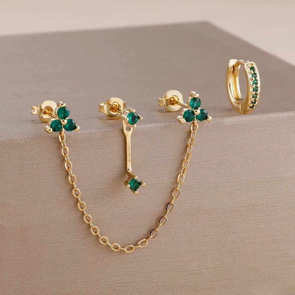 Boucles d'oreilles en chaîne dorée avec des pierres de zircon vert et une bague assortie.