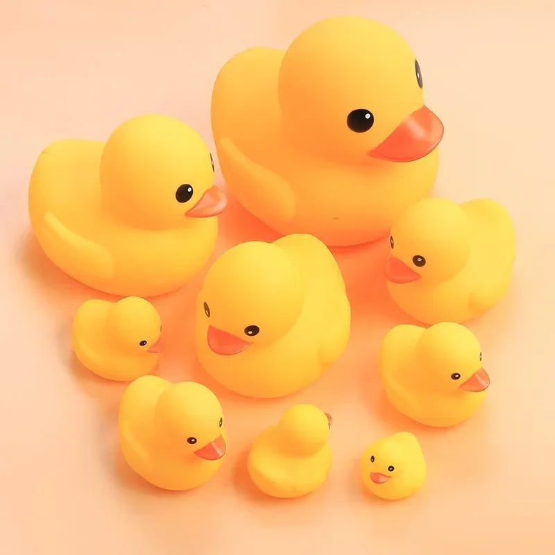 A collection of bright yellow rubber ducklings, some large and some small, arranged on a light background.