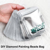 A hand holds a clear plastic bag filled with diamond painting beads for storage.