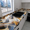 A kitchen countertop with a black sink featuring a marble effect film in shades of gold, brown, and gray.