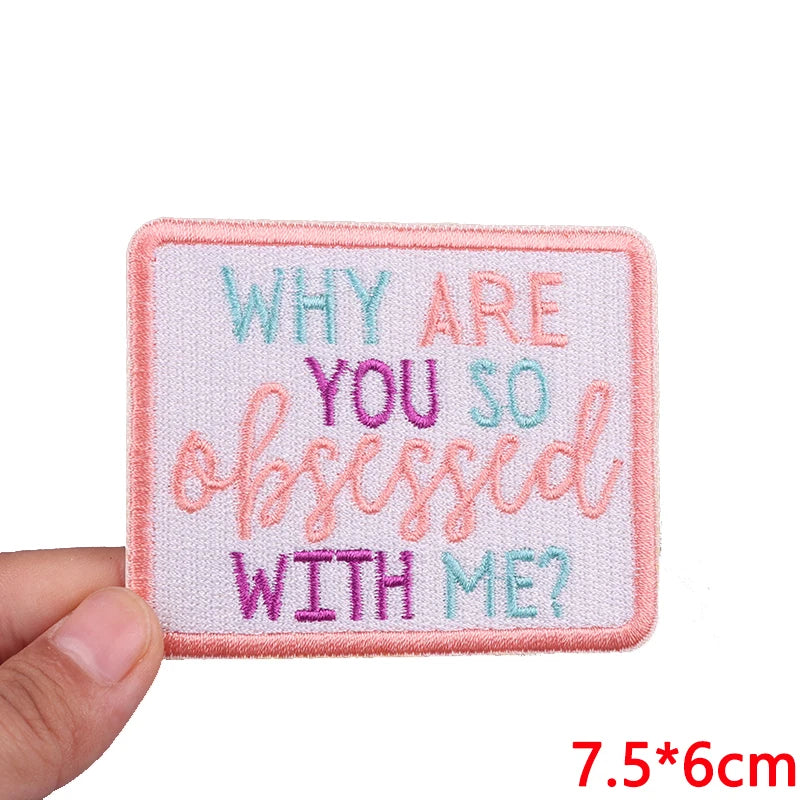 Pink embroidered patch with light blue and purple text asking Why are you so obsessed with me?