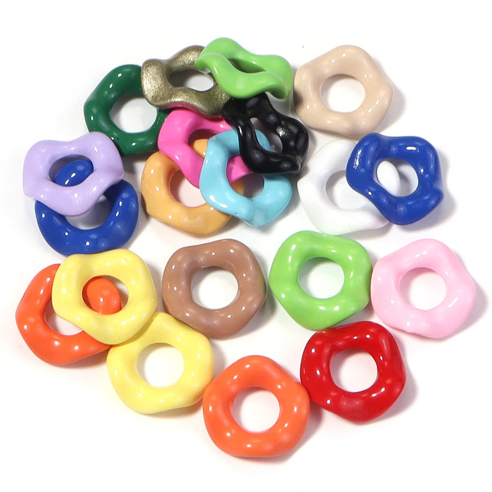 A collection of colorful acrylic spacer beads in various shades including green, purple, pink, yellow, and black.