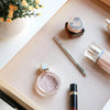 A close-up of a cosmetic product and various small items resting on a light beige drawer liner mat.