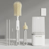 A set of silicone baby bottle brushes, including a main brush and two smaller brushes, displayed on a light gray surface.