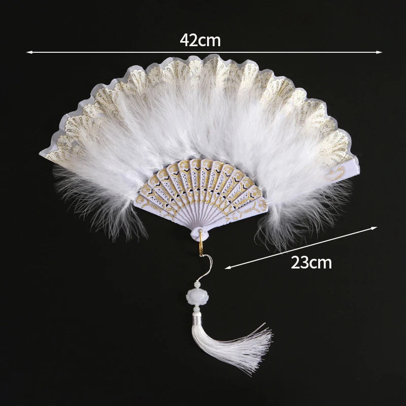 A white folding fan with a lace trim and golden edge, shown against a black background.