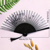A black and white vintage lace folding hand fan with a durable handle displayed against a light pink background.