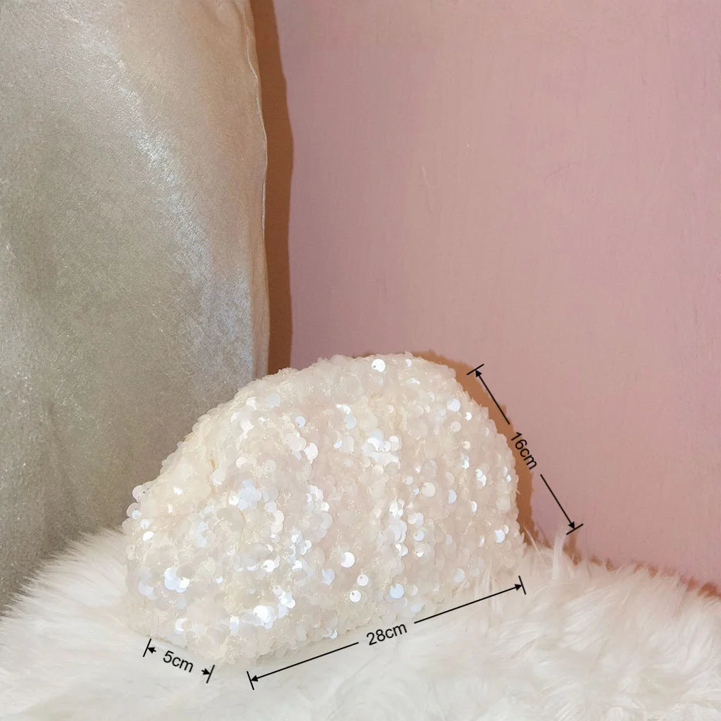A fluffy white beaded chain shoulder clutch bag resting on a pink wall.