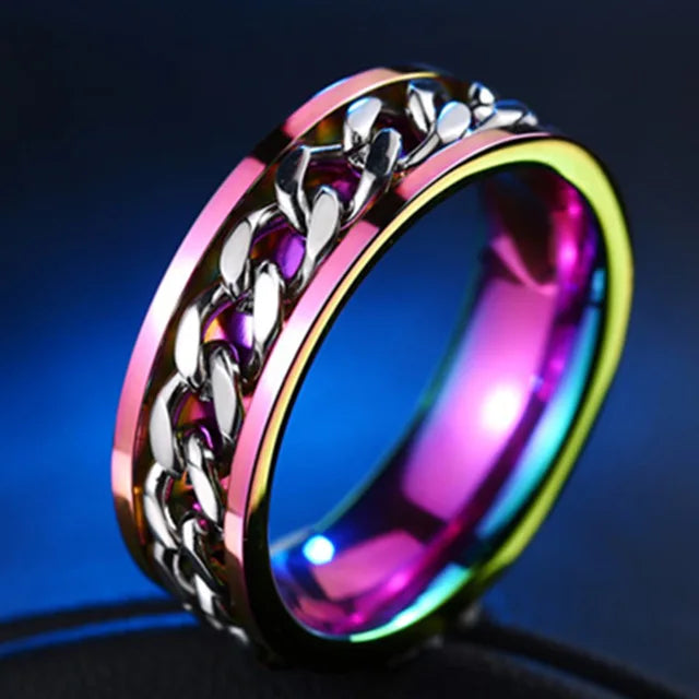 A close-up of a stainless steel spinner ring with iridescent pink and purple accents against a dark blue background.