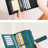 A close-up of a dark green leather bifold wallet with multiple card slots and a black zip-around closure being held by hands.
