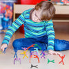 Ein Kind spielt mit bunten magnetischen humanoide Spielzeugen auf einer hellen Holzoberfläche.