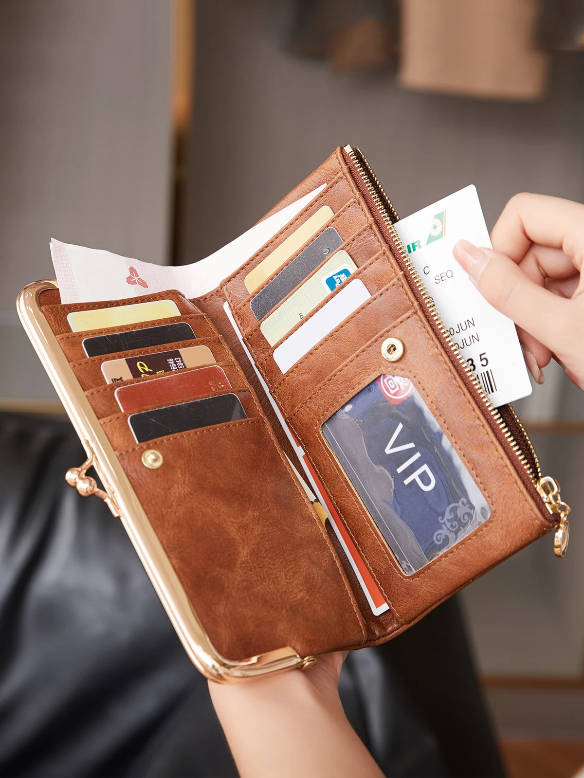 A brown leather wallet with a gold clasp is shown open, displaying various credit cards and an ID card.