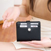 A hand holds a black bi-fold credit card wallet with a gold chain, demonstrating RFID protection.
