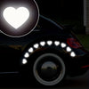 A black car wheel is decorated with multiple glowing heart stickers for night safety and car decoration.