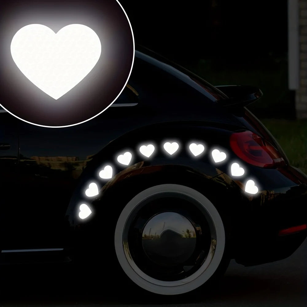 A black car wheel is decorated with multiple glowing heart stickers for night safety and car decoration.