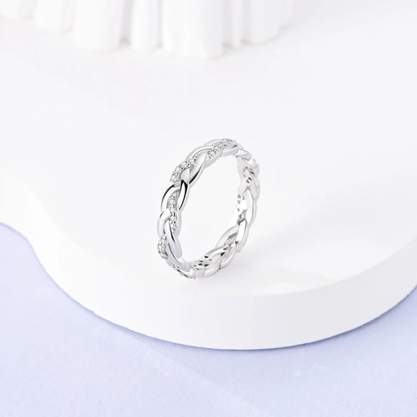 Primer plano de un anillo de plata con un intrincado diseño de hojas y pequeñas piedras de zirconia.