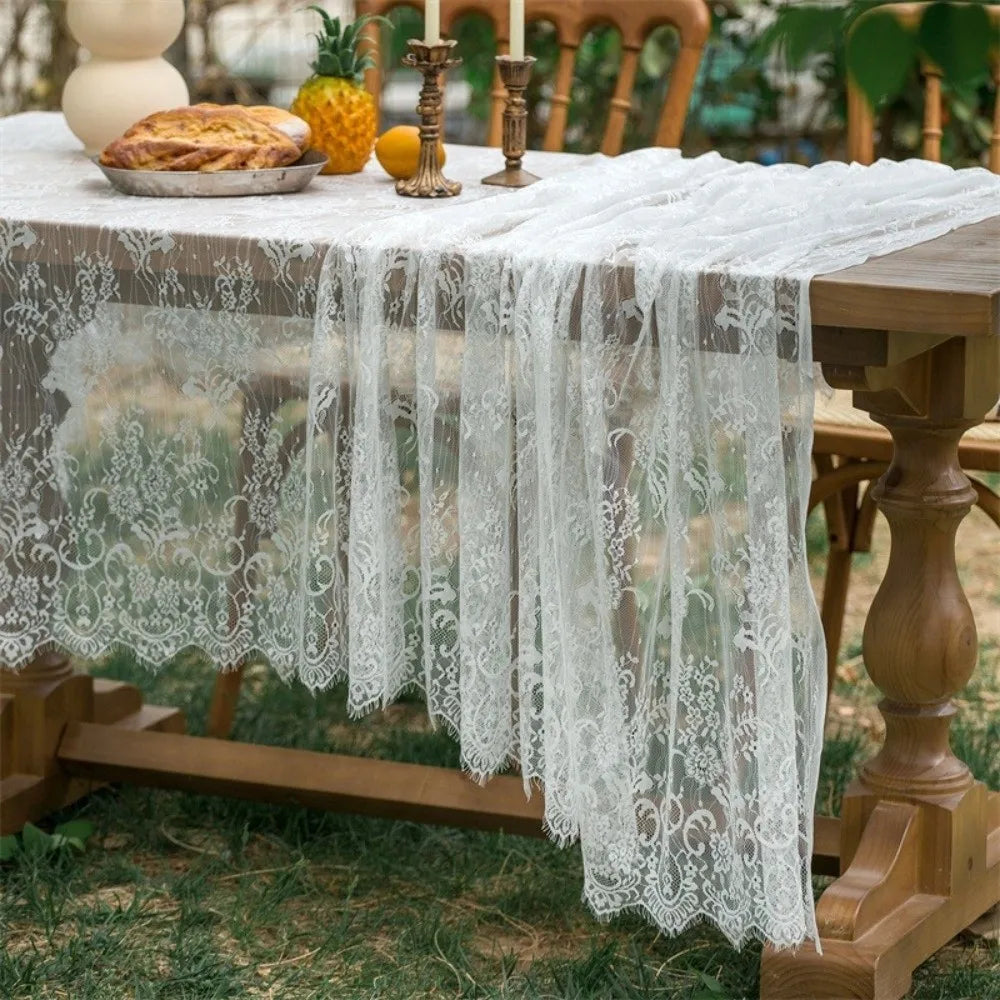 Elegant white lace tablecloth with French retro floral design draped over a wooden table.