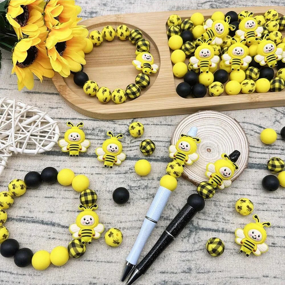 Yellow and black silicone bee beads for jewelry making and DIY crafts displayed on a wooden board.