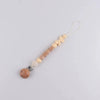 A beaded silicone pacifier clip lanyard with a name charm and a wooden teething sphere.