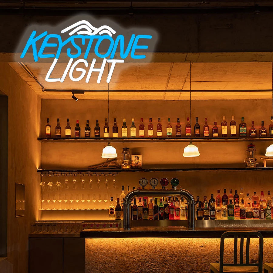 A glowing blue neon sign spelling KEYSTONE LIGHT illuminates a wooden bar shelf display.