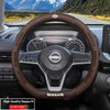 A close-up view of a brown leather steering wheel cover on a Nissan vehicle interior.