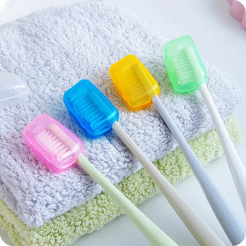 A collection of colorful protective toothbrush heads with white handles resting on a light green towel.
