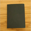 A black A6 Kraft paper blank notebook for sketching and journaling placed on a wooden surface.