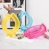 Three reusable U-shaped neck wraps in yellow, blue, and pink plastic resting on a white surface.