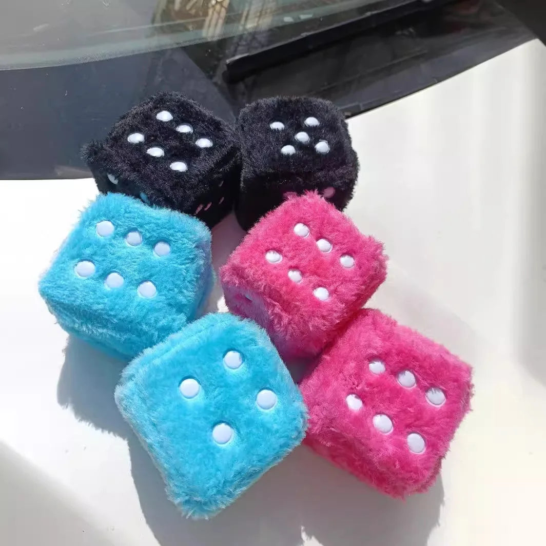A collection of plush velvet dice in black, pink, and blue colors.