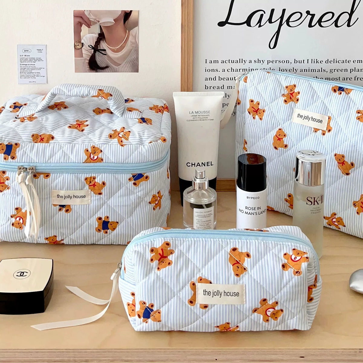 Hellblaue und weiße Layer-Make-Bag mit Bärenmustern, auf einer Holzoberfläche.