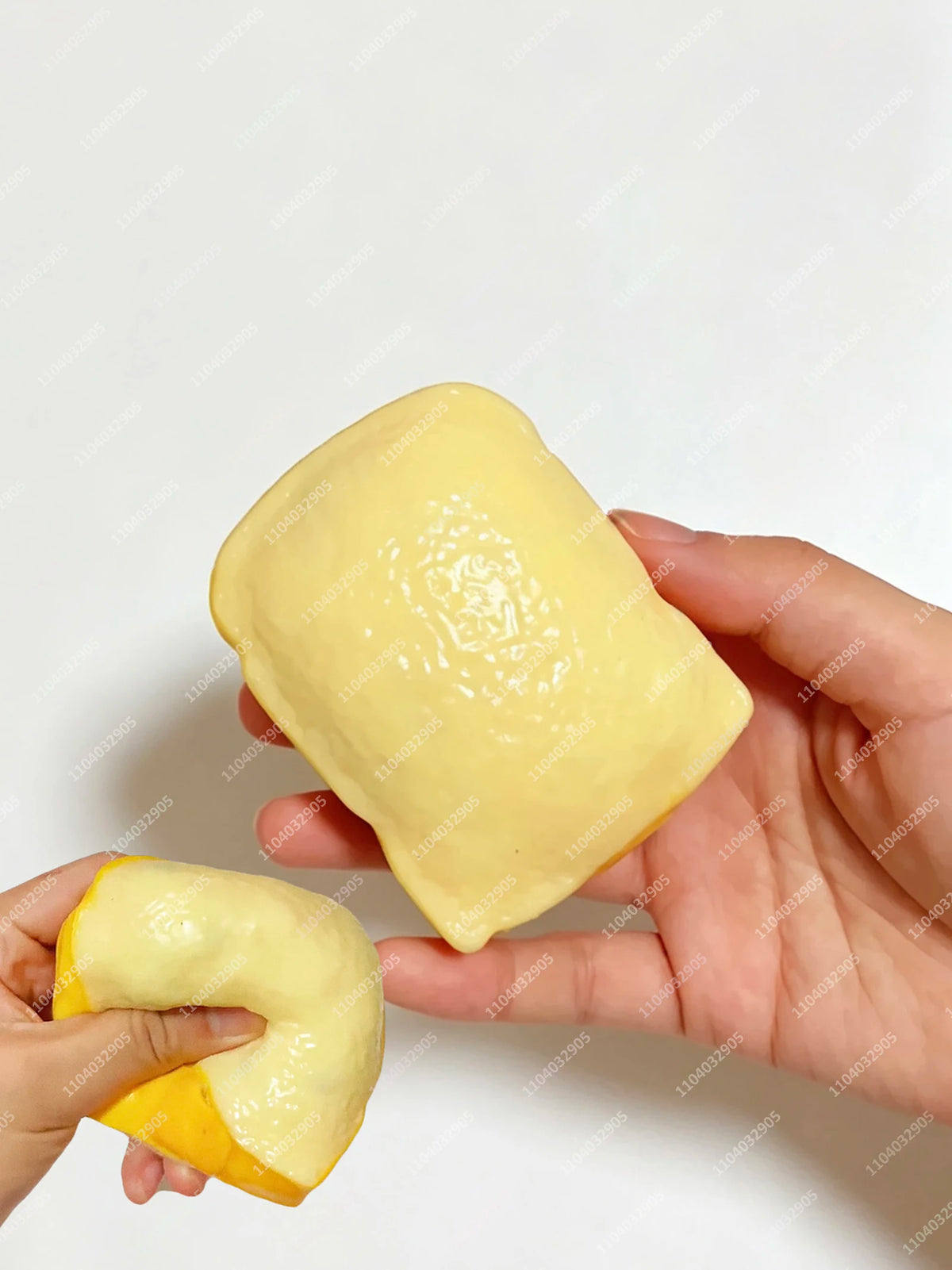 Eine Hand hält einen gelben, klebrigen Kartoffel-Stressball-Fidget-Spielzeug vor einem weißen Hintergrund.