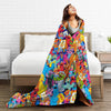 A woman is lying on a bed with a colorful Sesame Street Friends flannel throw blanket draped over her.