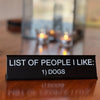 A black desk sign with white text listing Dogs as a favorite person.