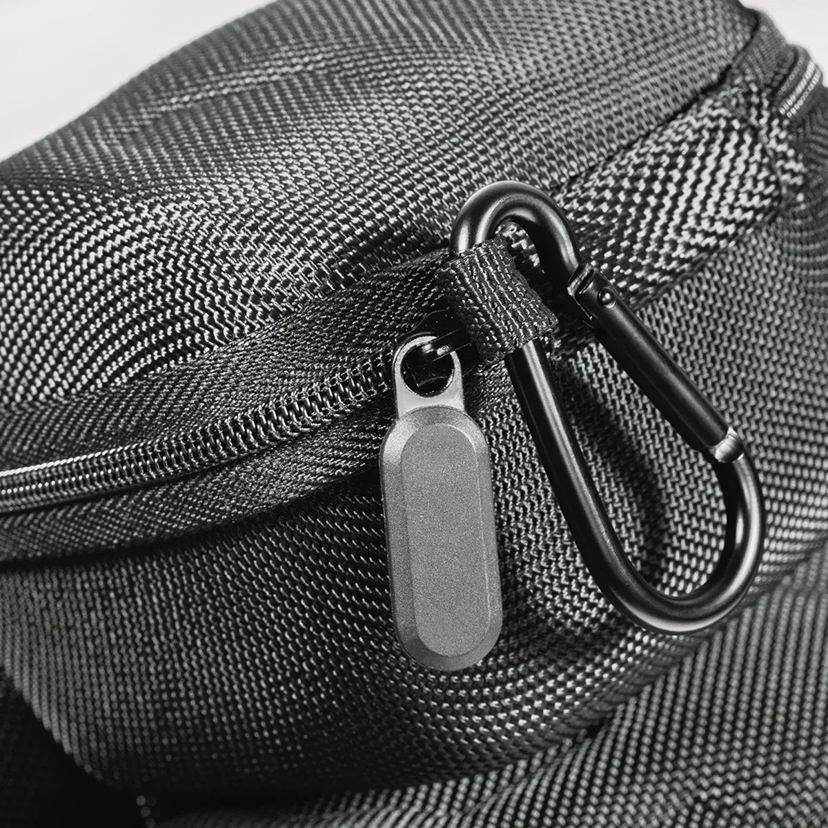 Close-up of a black woven fabric travel case with a zipper and metal clasp.