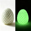 A white, textured fidget egg stress relief toy shown in two views: a bright white version and a glowing lime green version.