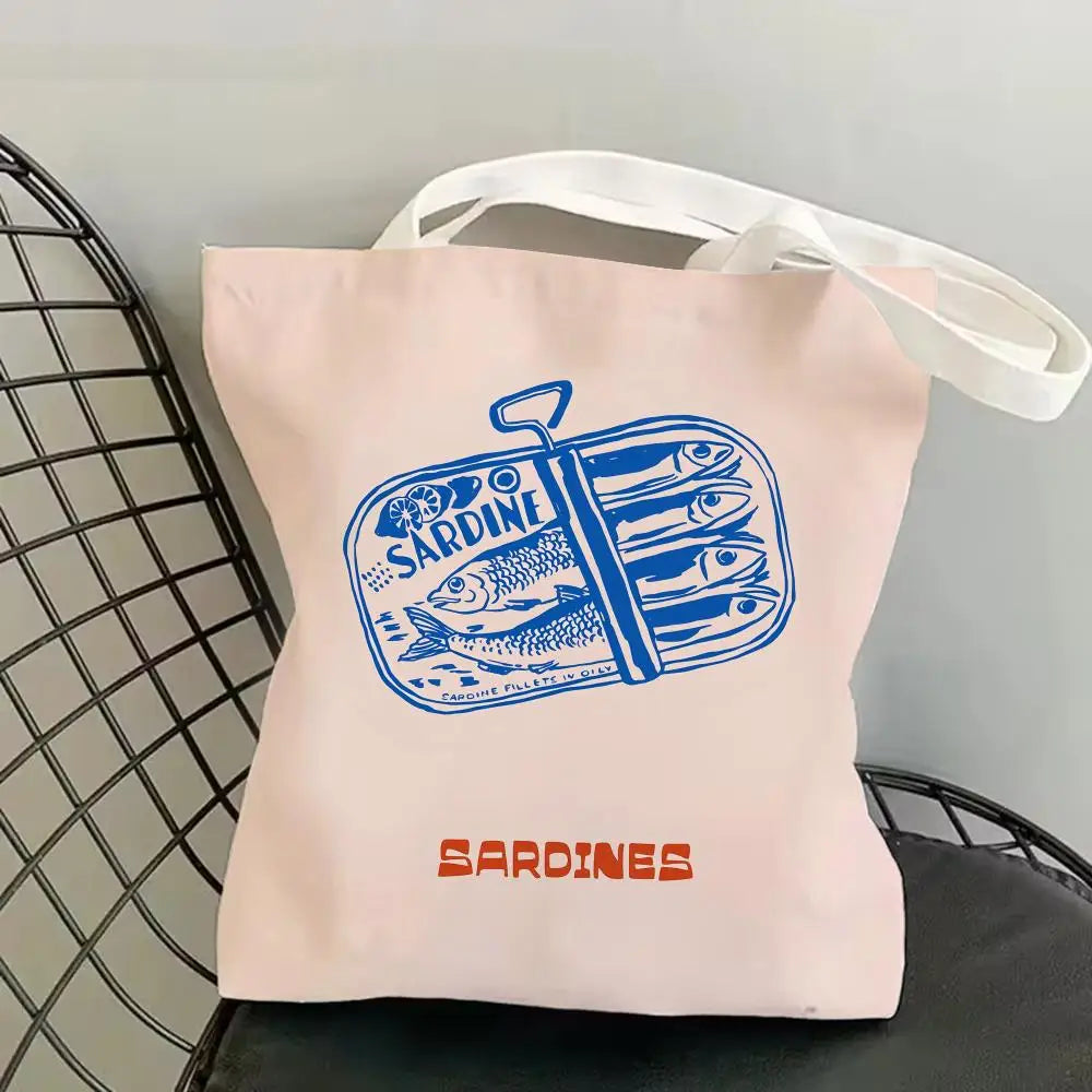 Pink canvas tote bag featuring a blue illustration of sardines.